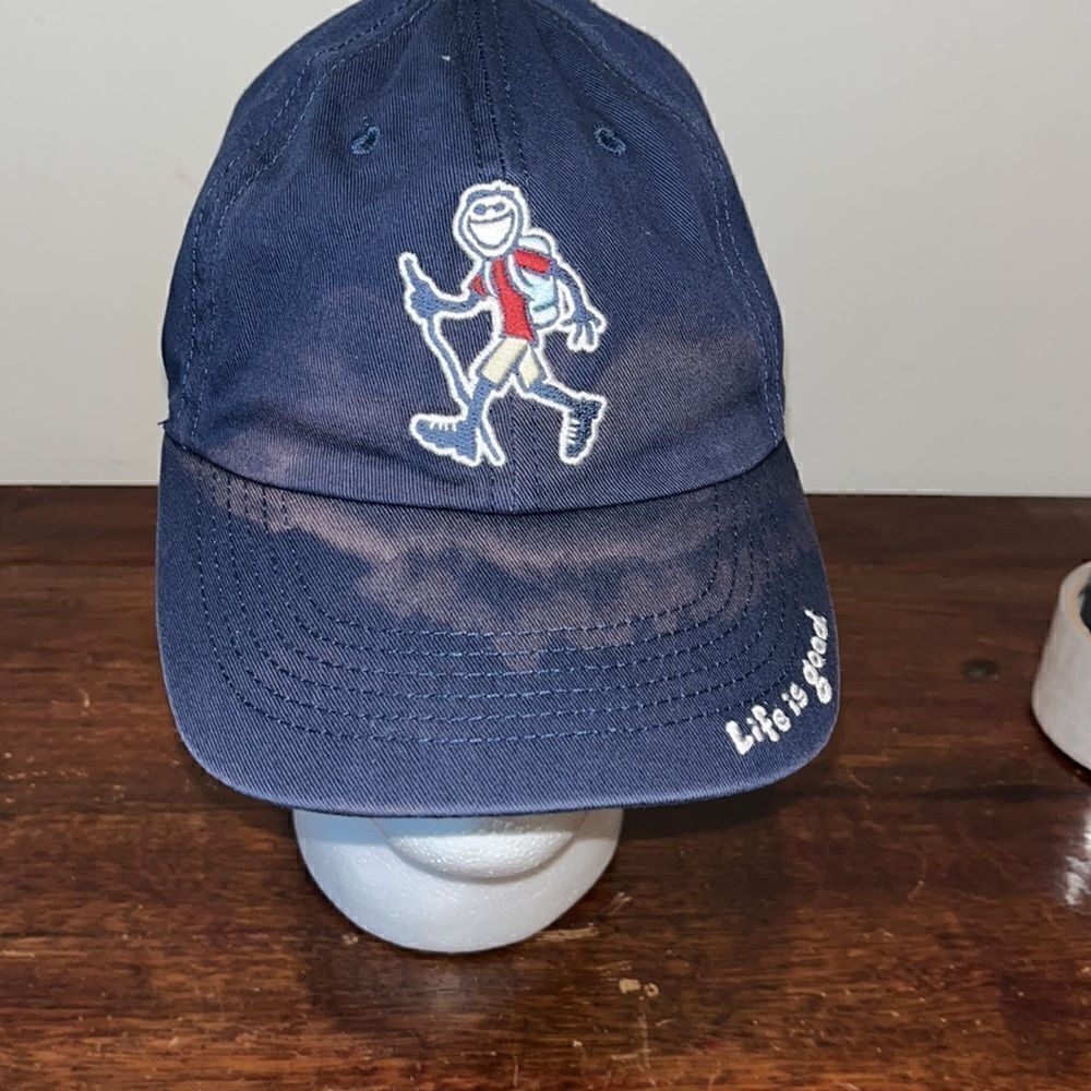 Worn dark blue life is good smiling Jake, hiking trail w/ stick cap hat